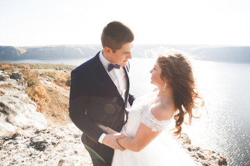 Elegant stylish happy wedding couple, bride, gorgeous groom on the background of sea and sky