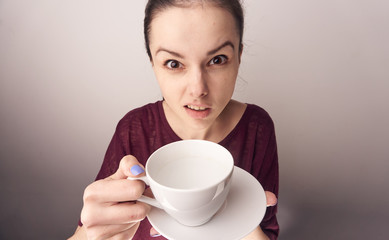 Beautiful young woman on a gray background holds a mug