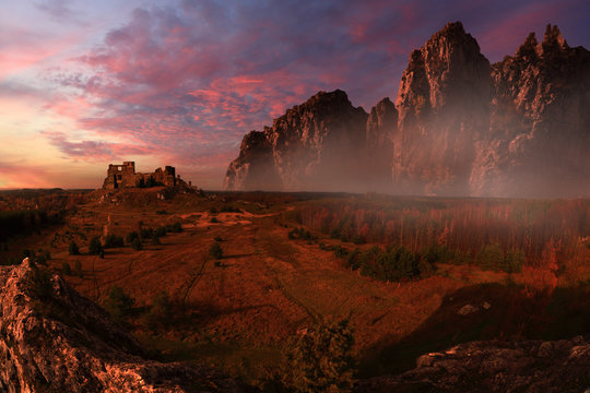 Fototapeta Antyczne ruiny zamku na wzgórzu oświetlone czerwonym zachodem słońca.