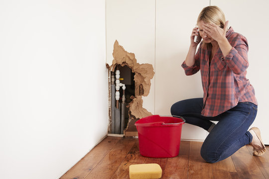 Middle Aged Woman With A Burst Water Pipe Phoning For Help