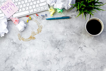 Clutter in office. Desk covered with crumpled paper and coffee stains. Grey background top view copyspace
