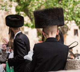 Orthodox jews in black hasidik costumes, lighting candle in the holiday of hanukah in the old city of jerusalem israel