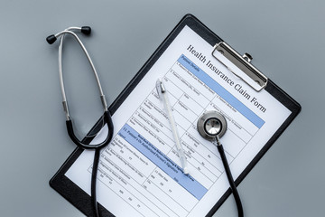 Health insurance for reception at the doctor. Document and stethoscope on dark grey background top view