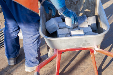 The worker removes the paving slab from the wheelbarrow. Repair of paving slabs. Workers laid paving slabs.