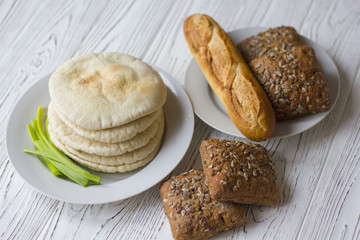 white and black bread and baguette on a wooden table