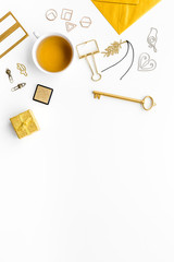 Office desk in trendy gold color. Glittering stationery near cup of tea   on white background top view copyspace