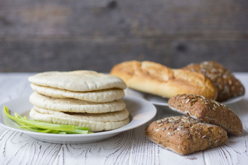 white and black bread and baguette on a wooden table