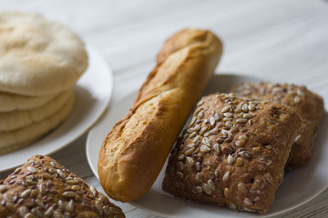 white and black bread and baguette on a wooden table