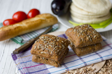 fresh bread with sunflower seeds, baguettes and tomatoes on a wooden table