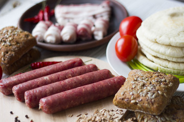 bacon, sausage, bread, parsley on a wooden table