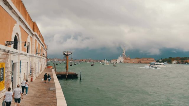 VENICE, ITALY, SEPTEMBER 7, 2017: A beautiful view of the Venice embankment on the Gande Canal, the waters of which are beating against the shore, along which people are strolling