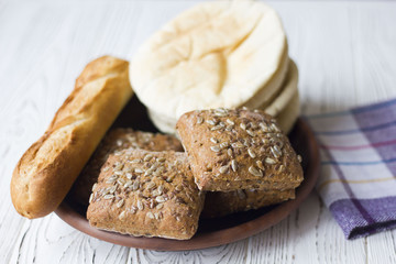 white and black bread and baguette on a wooden table