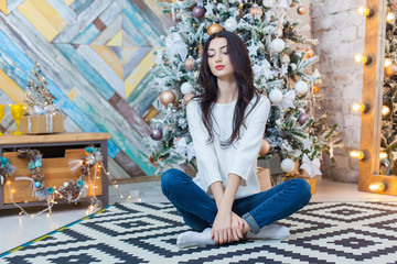 Christmas. Beautiful smiling girl. is sitting over christmas tree lights background. happy new year.