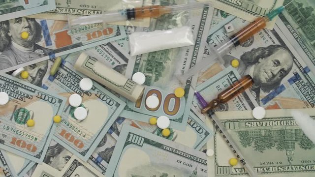 Pills, drugs, cocaine, syringe on dollar bank notes. The frame rotates counterclockwise.