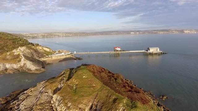 Mumbles Pier and lifeboat stations in Swansea Bay, UK, viewed over the middle island by Mumbles lighthouse