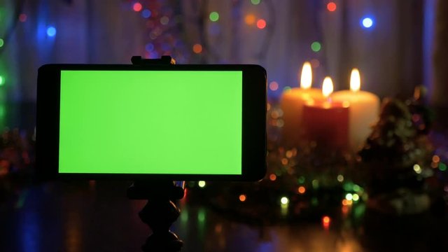 Smartphone with a green screen. New Year background blurred. A great opportunity to add your greeting video.