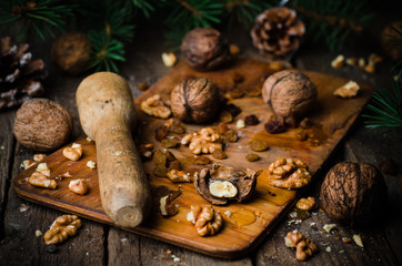 Whole and chopped walnuts with honey on vintage wooden background.Christmas mood, top view