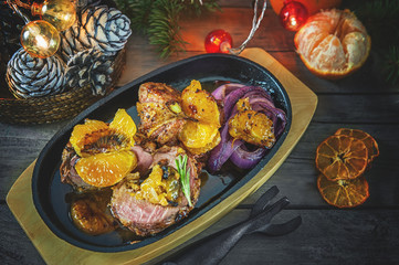 Roulade of duck breast fillets stuffed with Mandarin oranges, red onions and grilled mandarins on the Christmas table.