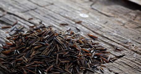 Heap of raw wild rice on an old wooden table