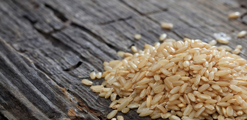 Heap of raw brown rice on an old wooden surface