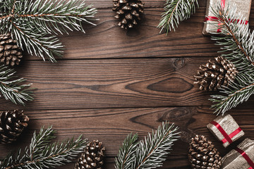 Brown wood background. Fir branches, decorative cones. Space for the message. Gifts for xmas. Christmas greeting card and new year. Xmas and Happy New Year composition. Flat lay, top view