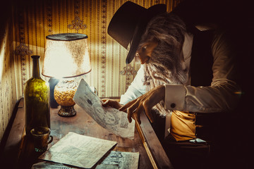 Fototapeta na wymiar Bearded man reads a mysterious letter in the dark room