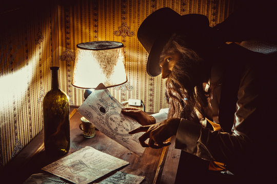 Bearded man reads a mysterious letter in the dark room