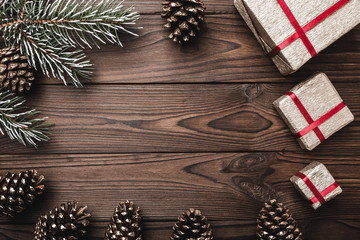 Brown wood background. Fir tree, decorative cones. Message space for Christmas and New Year. Gifts for xmas. Greeting card. Xmas and Happy New Year composition. Flat lay, top view