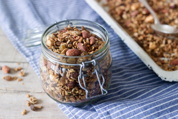 Homemade granola in a glass jar and on a baking sheet. Rustic style.