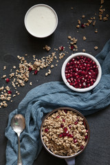 Ready-made healthy breakfast - muesli or granola with pomegranate seeds and fresh natural yoghurt on rustic wooden background, top view