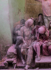 People sitting on the street in the villages of Barsa and Mathura India during the holi festivals days and are covered with powder in all different colors especially pink and red