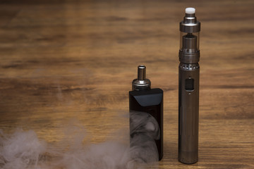 Obraz na płótnie Canvas Popular vaping mod device.Upgrade parts for a modern vaporizer electronic cigarette device,parts.A new model of the device, the micro-coil clearomizer, on wooden background.