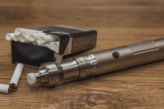 Popular vaping mod device.Upgrade parts for a modern vaporizer electronic cigarette device,parts.A new model of the device, the micro-coil clearomizer, on wooden background.