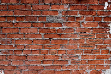 Background of a building wall from an old broken rough red brick close-up with a soft focus.