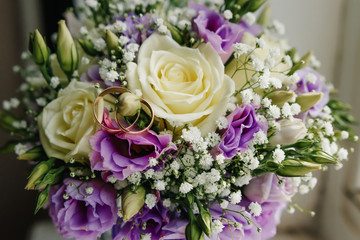 Wedding rings with bridal bouquet lying on the morning of the bride.