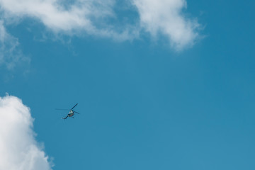 Flying small helicopter high in a blue cloudy sky.