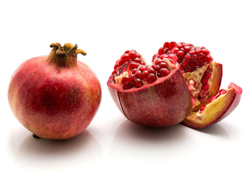Two pomegranate isolated on white background one whole and one open.