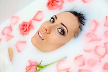 Obraz na płótnie Canvas young beautiful girl in a bathtub with milk and roses