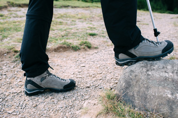 Close-up trekking shoes, bottom view. Man hiking in mountain on rocky path. Active outdoor recreation