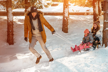 father taking family on a sledge snow ride