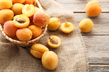 Sweet apricots in basket with sackcloth on grey wooden table