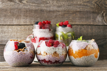 Chia pudding with berries in glasses on grey wooden table
