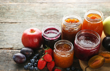 Glass jars with different kinds of jam on wooden table