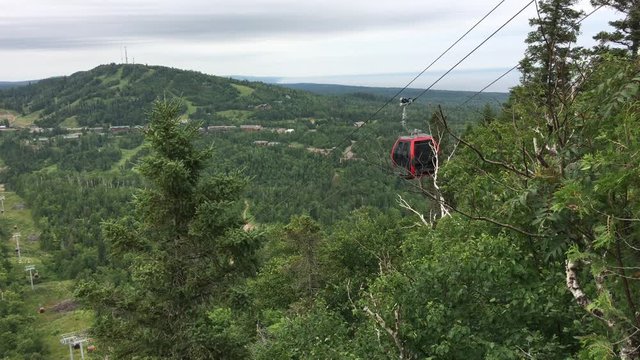 High atop a mountain in northern Minnesota a gondola tram climbs up cable line towards top.