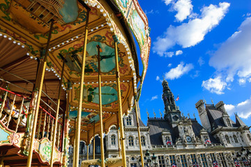 Paris, France. Old carousel and Hotel de Ville decorated with flags at background in sunny day. 