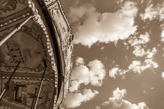 Old Parisian carousel against sky with clouds in sunny day. Sepia. 