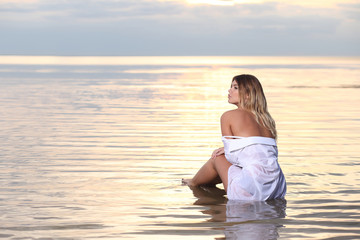 Fototapeta na wymiar fashion photography with pretty woman in the water at sunset