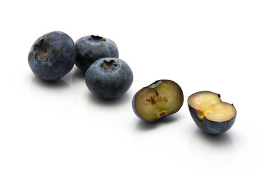 Bog blueberries isolated on white background three whole and one cut in half.