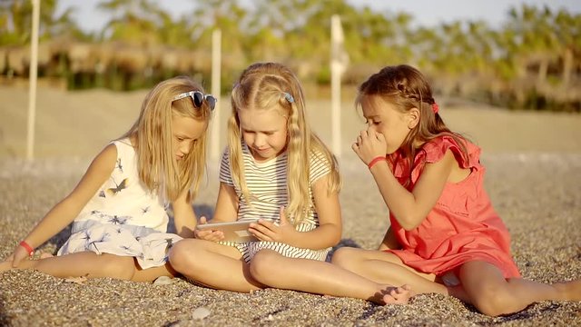 Adorable little girls are enjoying the game on a beach.