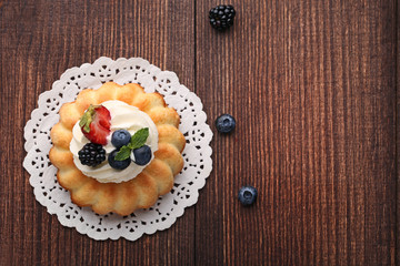 Delicious bundt cake with berries on brown wooden table